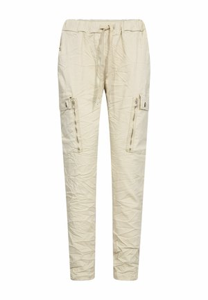 Pantalon cargo beige avec taille élastique, cordon de serrage, poches latérales zippées et boutonnées, et bas resserrés.