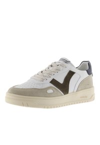 Sneaker bianca e beige con dettagli in suede, caratterizzata da un design a V marrone e una suola beige chiaro. Punta tonda e lacci piatti.