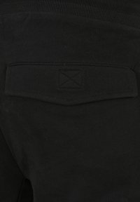 Zwarte sweatpants met een gestructureerde stof, elastische tailleband en een enkele achterzak met een gestikt vierkant logo detail.