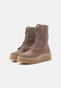 Kamelowe zamszowe botki na sznurówki z żeberkową, grubą gumową podeszwą, sięgające do połowy łydki, z bocznym zamkiem błyskawicznym, prezentowane na białym tle.
