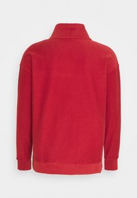 Sudadera roja de manga larga con cuello alto, puños y dobladillo acanalados, vista desde la parte posterior sobre un fondo blanco.