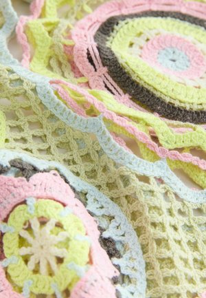 Nærbillede af pastel-farvet hæklet stof med cirkulære og netmønstre i pink, gul, blå og brune tråde.