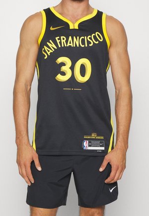 Mand iført sort og gul San Francisco basketballtrøje med nummer 30 og sorte Nike-shorts.