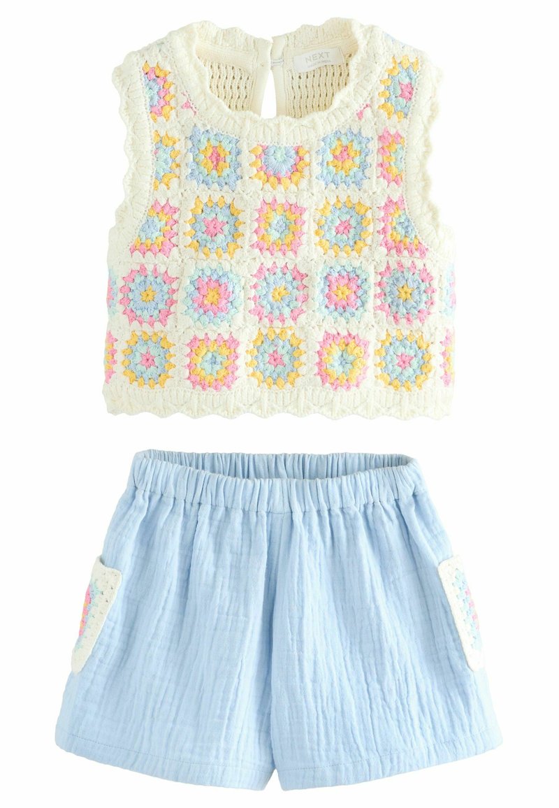 Häkel-Style Top mit pastellfarbenen Quadraten in Gelb, Pink und Blau; kombiniert mit hellblauen Shorts mit weißen Paspeltaschen.