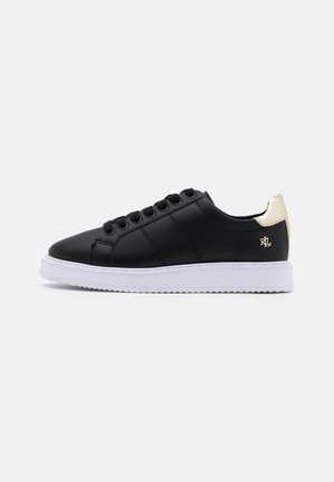 Czarny niski sneaker z białą podeszwą, czarnymi sznurowadłami i złotą patką na pięcie z małym logo RL po boku.