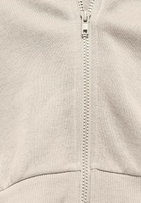 Giacca leggera grigia con zip, realizzata in un tessuto morbido, con polsini e orlo a coste e una cerniera a contrasto. Design semplice e moderno, senza fantasie.