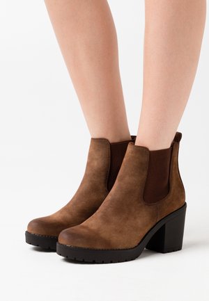 Braune Wildleder-Stiefel mit runder Zehenpartie, elastischen Seiteneinsätzen und Blockabsatz, ausgestattet mit einer strukturierten Sohle für besseren Grip.