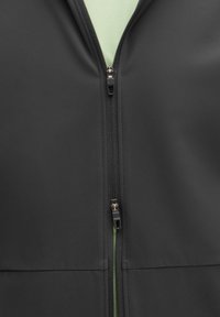 Zwarte zip-up jas met een soepele textuur, een vooraanstaande rits met een lus om aan te trekken, en een contrasterende groene binnenzijde.