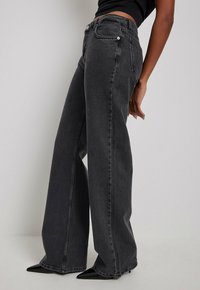 Wijde zwarte spijkerbroeken van denim, met een klassieke knoopsluiting, twee voorzakken en een gladde textuur. Op maat gemaakt voor een stijlvolle uitstraling.