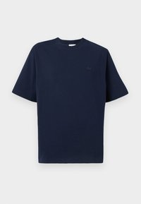 T-shirt en coton bleu marine à manches courtes, col rond et petit logo noir sur la poitrine gauche. Texture douce, coupe droite.