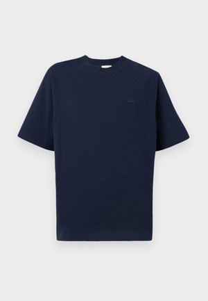 T-shirt di cotone blu navy con maniche corte, colletto rotondo e un piccolo logo nero sul lato sinistro del petto. Tessuto morbido, design a taglio dritto.