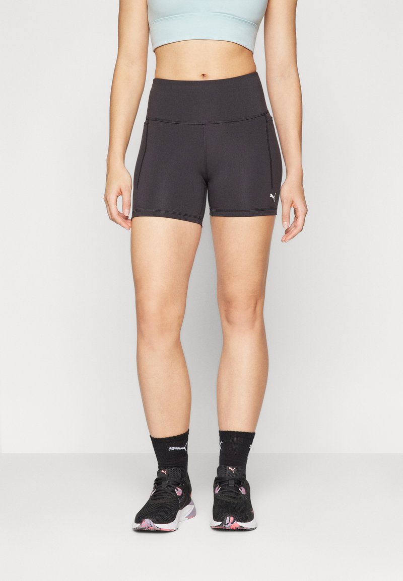 Pantaloni sportivi neri con vita alta, cuciture piatte e tasche laterali. Abbinati a scarpe da ginnastica nere e calzini a fantasia per un contrasto.