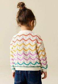 Gebreid vest in roomwit met een geschulpte patroon in oranje, geel, roze en turquoise. Geribbelde manchetten en zoom, met een losse pasvorm.