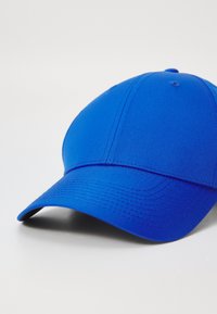 Casquette de baseball bleue avec une texture de tissu lisse, une visière courbée et des détails brodés le long des coutures. Aucuns logos ni graphiques visibles.