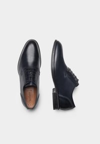 Scarpe in pelle blu scuro dal design elegante, con una finitura liscia, punta arrotondata e tacco basso. Presentano cuciture decorative.