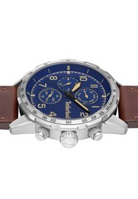 Orologio cronografo con quadrante blu, cassa in acciaio inossidabile argento, cinturino in pelle marrone, indicatori delle ore dorati e due sottoquadranti. Logo Timberland in evidenza.