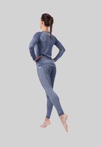 Langsleeve blauwe sporttop met textuurstof en lichtgrijze accenten, gecombineerd met gestreepte blauwe leggings, beide nauwsluitend en rekbaar.