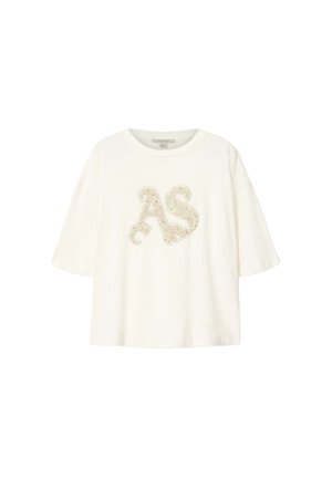 T-shirt blanc à manches courtes avec encolure arrondie, présentant des lettres décoratives "AS" beiges ornées de motifs floraux sur le devant.