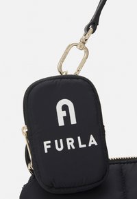 Czarna torba z wyściółką, o teksturowanym wykończeniu, z wyraźnym białym logo "FURLA" i złotą klamrą. Kompaktowy i funkcjonalny design.