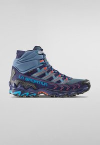 Wysokie buty trekkingowe w kolorze granatowym i turkusowym z czerwonymi akcentami; posiadają teksturowaną syntetyczną cholewkę, gumową podeszwę oraz regulowany system sznurowania.