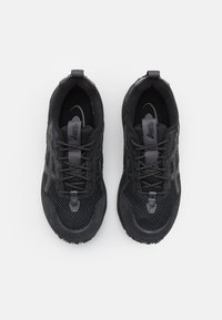 Svarta sportskor i mesh och mocka, med runda snören, en upphöjd häl och en strukturerad gummisula.