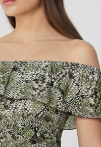 Abito off-the-shoulder in tessuto stampato verde e nero a serpente. Collo arricciato, corpetto aderente e dettagli di superficie testurizzati.