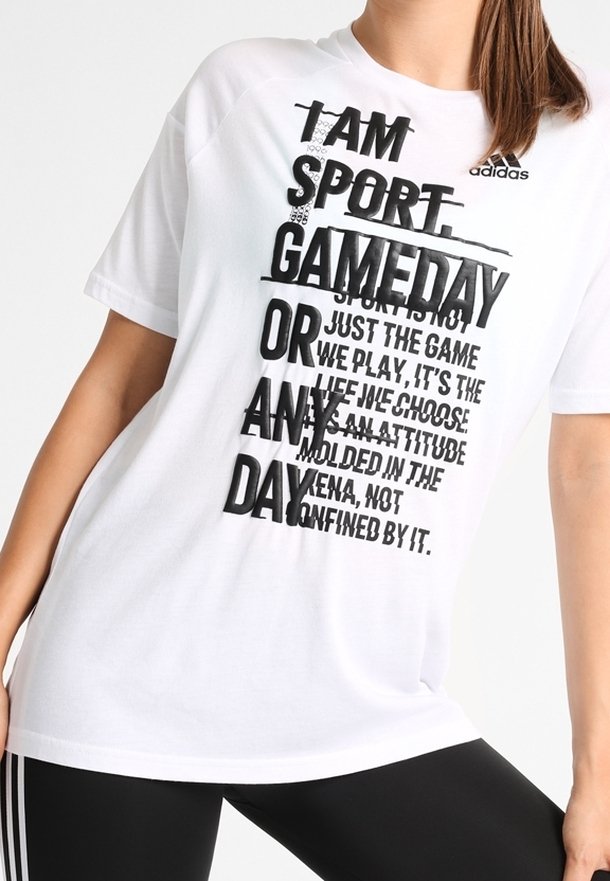 Bílé bavlněné tričko s výrazným černým textem obsahujícím fráze o sportu a postoji. Obsahuje logo Adidas a střih s volným střihem.