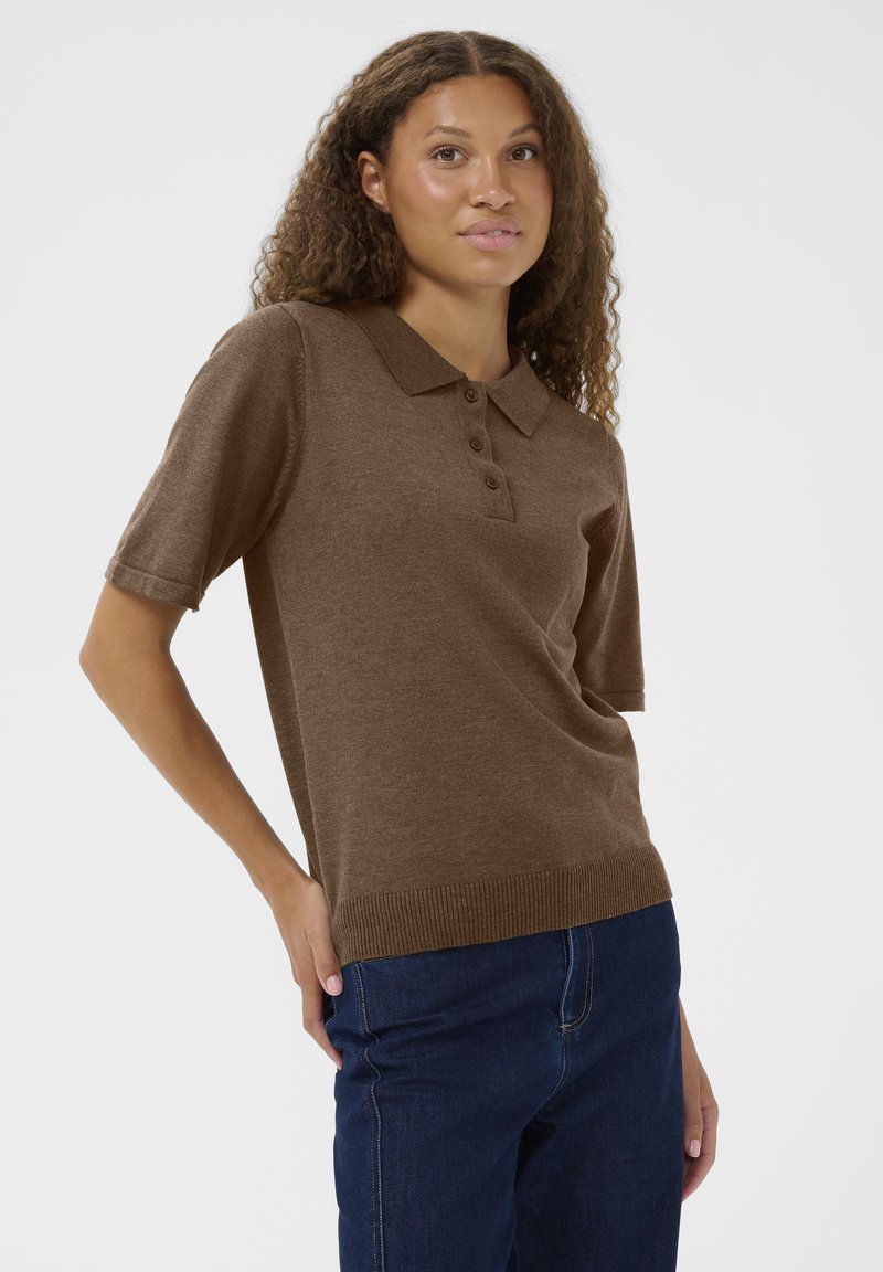 Barna rövid ujjú polo póló gallérral, három gombos kivágással és bordázott aljjal. Sötétkék farmerral viselve, sima textúrával.