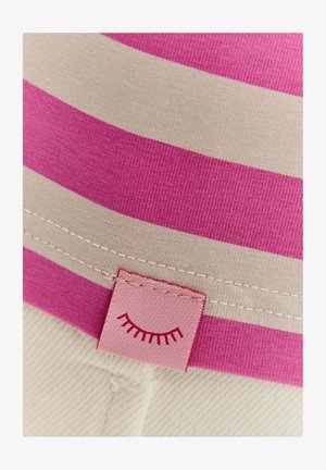 Pruhovaná tkanina s širokými růžovými a béžovými pruhy, s růžovou etiketou, která na lemu zobrazuje jednoduchou grafiku řas. Měkká textura.