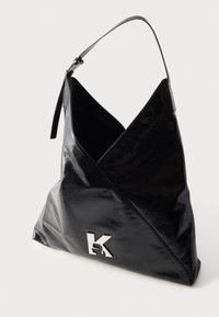 Czarna skórzana torebka z trójkątnym złożonym wzorem, pojedynczym regulowanym paskiem i srebrnym logo "K" z przodu.