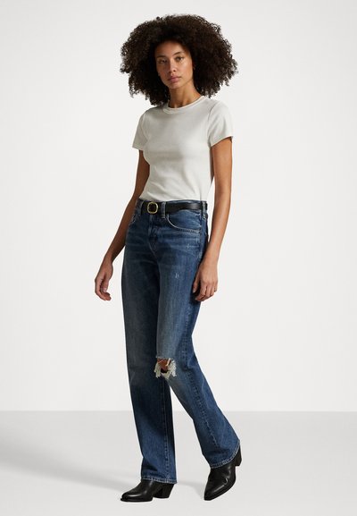 Lys grå t-skjorte med korte ermer, kombinert med mørkeblå slitte straight-leg jeans og svarte høye støvletter, fremhevet av et svart belte.