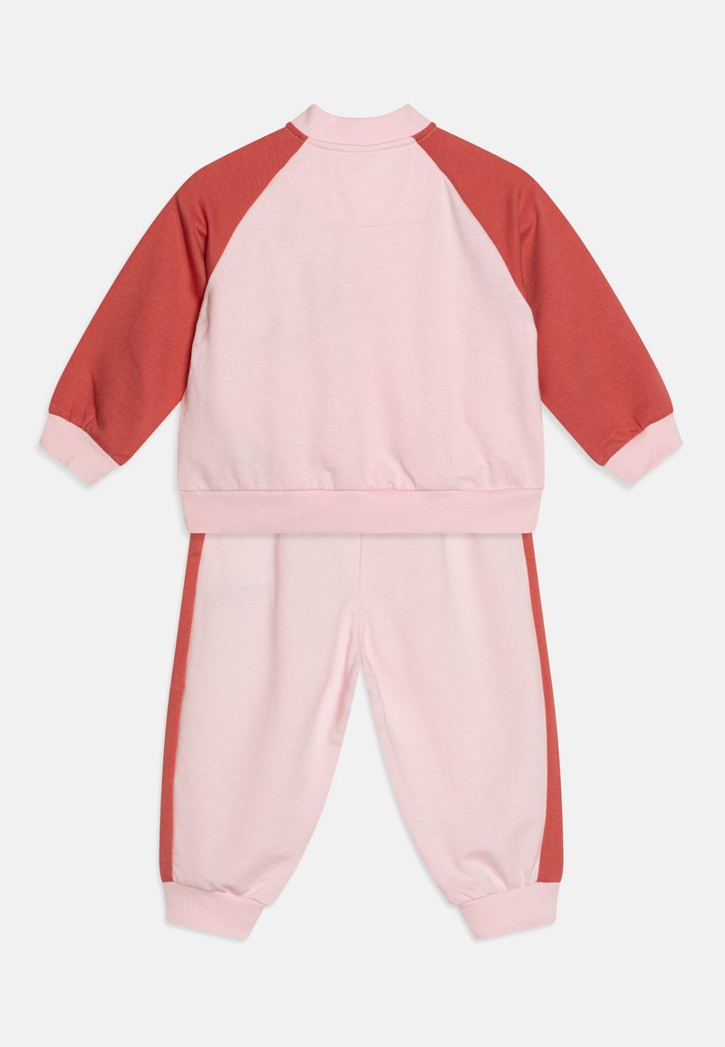 Ensemble de survêtement pour enfants composé de deux pièces : un haut de couleur rose clair avec des manches raglan rose foncé, et un pantalon assorti avec des bandes latérales rose foncé, des poignets et une taille élastiques.