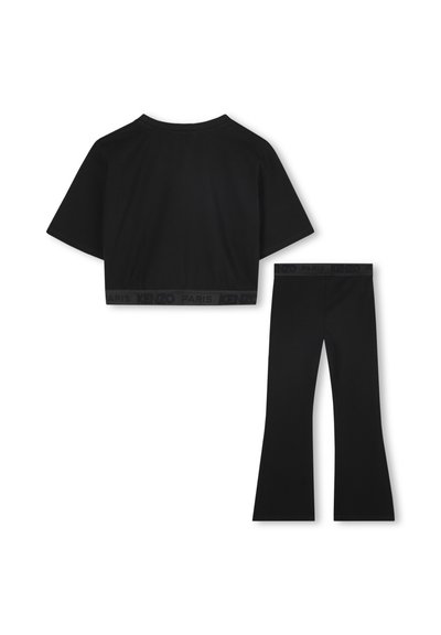 Top corto nero con maniche corte e scollatura rotonda abbinato a leggings neri a gamba ampia, entrambi con un cinturino elastico con logo.