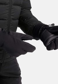 Guanti neri mostrati sulle mani, caratterizzati da un tessuto morbido e dettagli in pelle, progettati con un design a dita divise per garantire destrezza e calore.