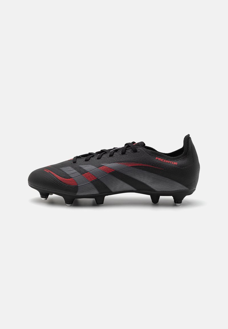 Black soccer cleat with a textured upper, gray and red stripes, lace-up design, and conical studs for traction. The word "Predator" is visible.