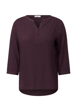 Blouse violette froncée avec un col rond, patte à trois boutons et manches trois quarts ; texture douce et design d'ourlet incurvé.