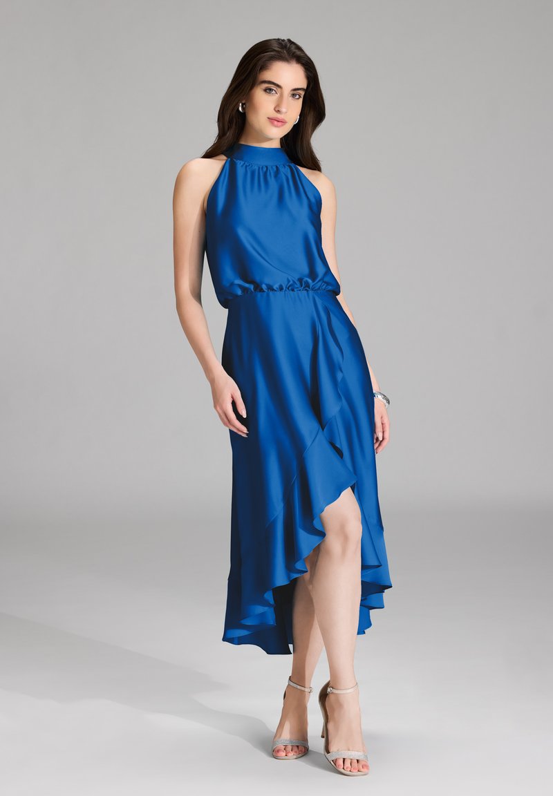 Sininen halterneck-mekko satiinista, joissa on tiukka yläosa ja röyhelöinen epäsymmetrinen helma. Yhdistetty hopeisiin korkokenkiin. Sujuva pinta.