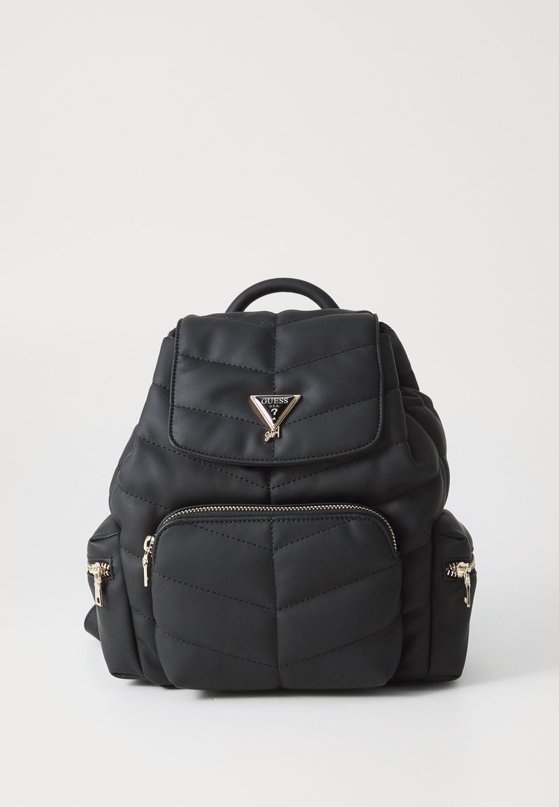 Sac à dos matelassé noir avec quincaillerie dorée, comportant une poignée supérieure, une poche zippée à l'avant et le logo de la marque sur le rabat. Matériau doux et texturé.