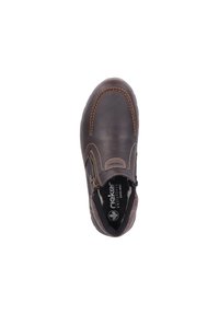 Chaussure slip-on en cuir marron avec coutures beiges, bout rond et fermeture éclair. L'intérieur présente une doublure douce avec une marque visible.