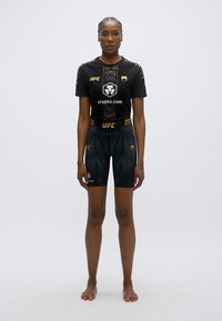 Tenue de sport noire UFC composée d'un haut à manches courtes et d'un short ajusté, avec des accents dorés et un design texturé, fabriquée en matériau léger.