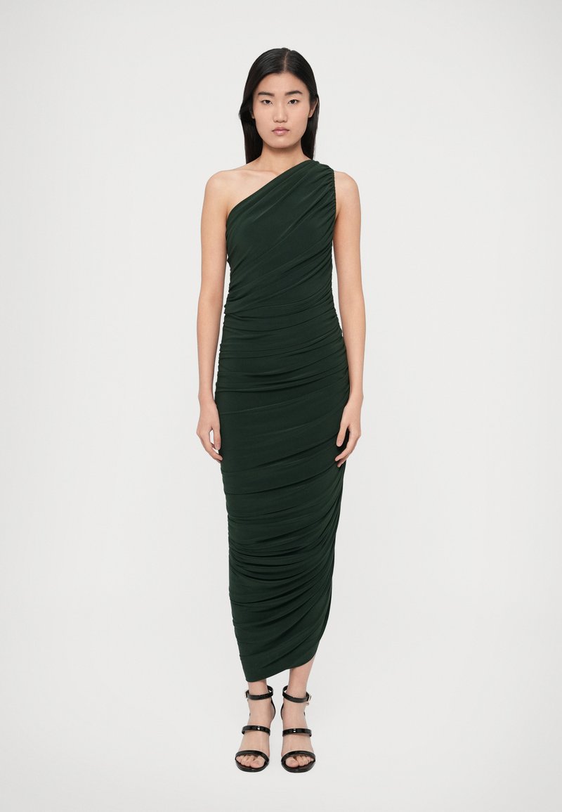 Jednokrčné tmavozelené šaty dĺžky po zem s nariasenou textúrou. Štylizované s čiernymi sandálmi na členok.