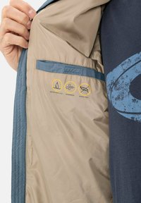 Wasserabweisende Jacke mit einem hellbraunen Innenfutter und blauen Akzenten. Verfügt über eine glatte Textur und Symbole, die winddichte und daunenfreie Eigenschaften anzeigen.