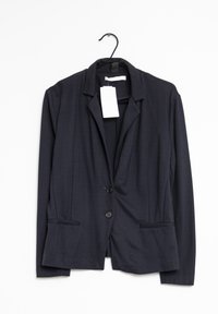 Blazer bleu marine foncé en tissu lisse, avec un col à crans, deux boutons et deux poches latérales. Étiquette attachée au col.