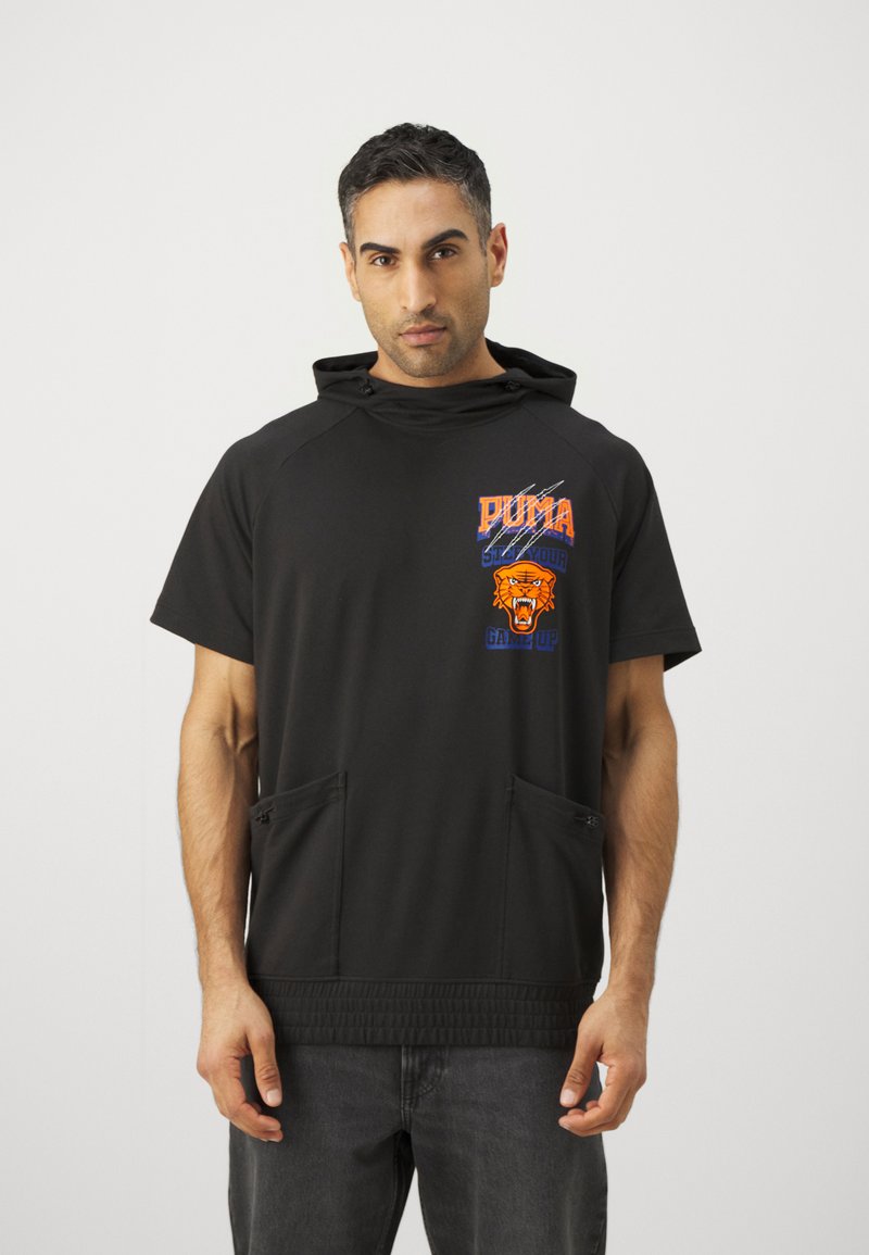 Sudadera corta de manga corta negra con capucha estructurada, que presenta dos bolsillos frontales con cremallera y un estampado gráfico en naranja y azul en el pecho.