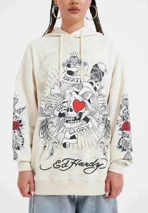 Cream hoodie featuring bold graphic prints of a skull, roses, and text on the front and sleeves. Oversized fit with drawstring hood.