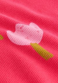 Rózsaszín anyag, amely stilizált virágmintával rendelkezik, világos rózsaszín szirmokkal és zöld szárakkal. A textúra bordázott és enyhén texturált.