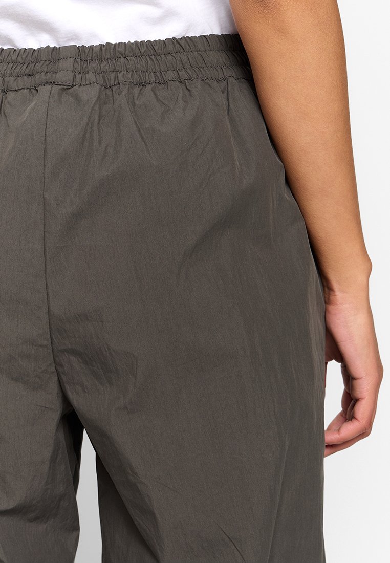 Hose in dunkelgrau mit elastischem Bund und lockerer Passform, aus leichtem Stoff gefertigt, mit glatter Oberfläche und dezenten Faltendetails.