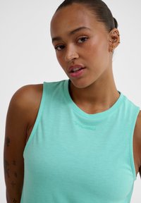 Helles türkisfarbenes Tanktop mit rundem Halsausschnitt und ärmellosem Design. Verfügt über ein dezentes Logo-Detail und einen weichen, strukturierten Stoff.