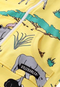 Geel zip-up hoodie met dierenpatronen, waaronder een zebra en een neushoorn, gemaakt van katoen met een zachte textuur. Inclusief een voorzak.