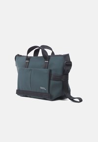 Green waterproof bag with two black handles, adjustable strap, and a front pocket. Features a zipper closure and a sturdy base.